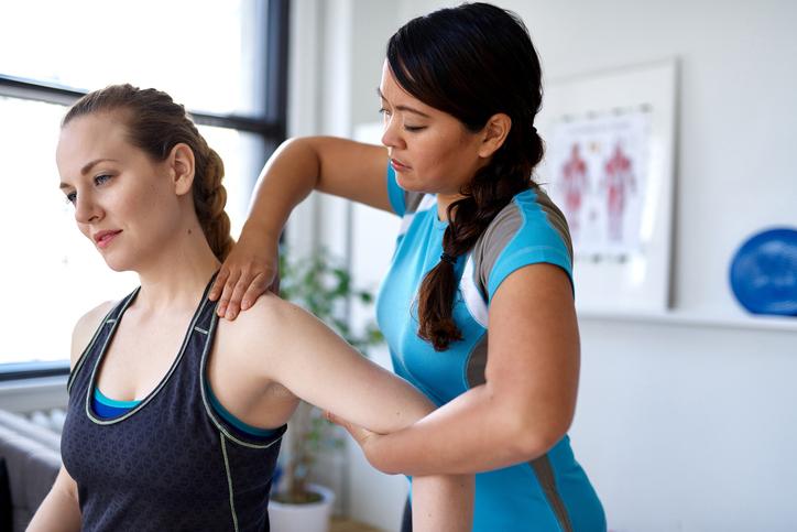 Physiotherapist mobilising shoulder joint of a female patient to treat shoulder pain