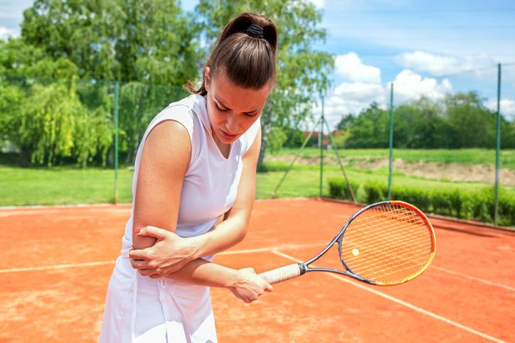 Female playing tennis with elbow pain / tennis elbow Female playing tennis with elbow pain / tennis elbow
